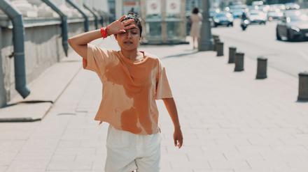 Eine junge Joggerin läuft verschwitzt die Straße entlang.