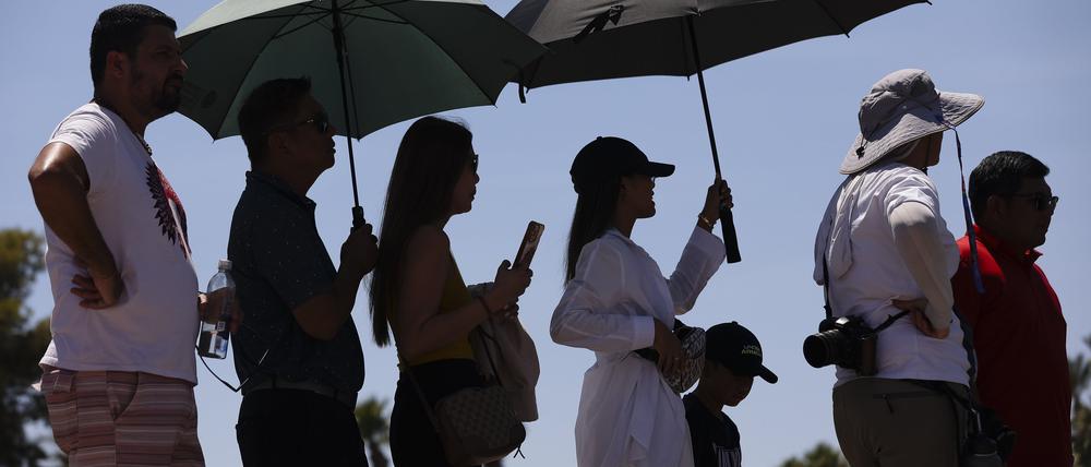 Las Vegas: Menschen tragen Regenschirme, um sich vor der Sonne zu schützen, während sie darauf warten, ein Foto am „Welcome to Las Vegas“-Schild zu machen.