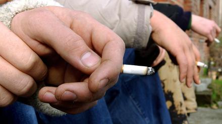 Drei Jungen mit einer Zigarette in der Hand.