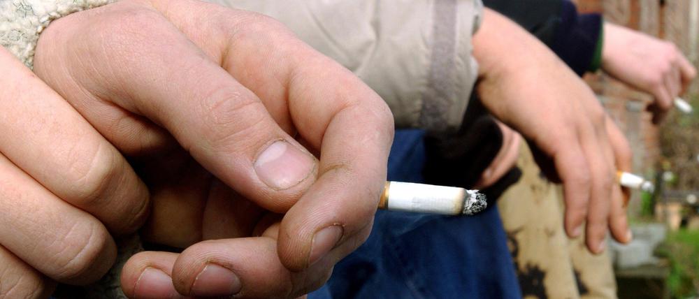 Drei Jungen mit einer Zigarette in der Hand.