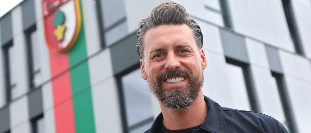Der neue Trainer Sandro Wagner posiert vor der Geschäftsstelle des FC Augsburg.