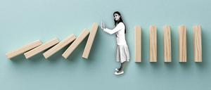 Illustration zum Thema „Grenzen setzen“: Eine Frau stoppt fallende Dominosteine.
