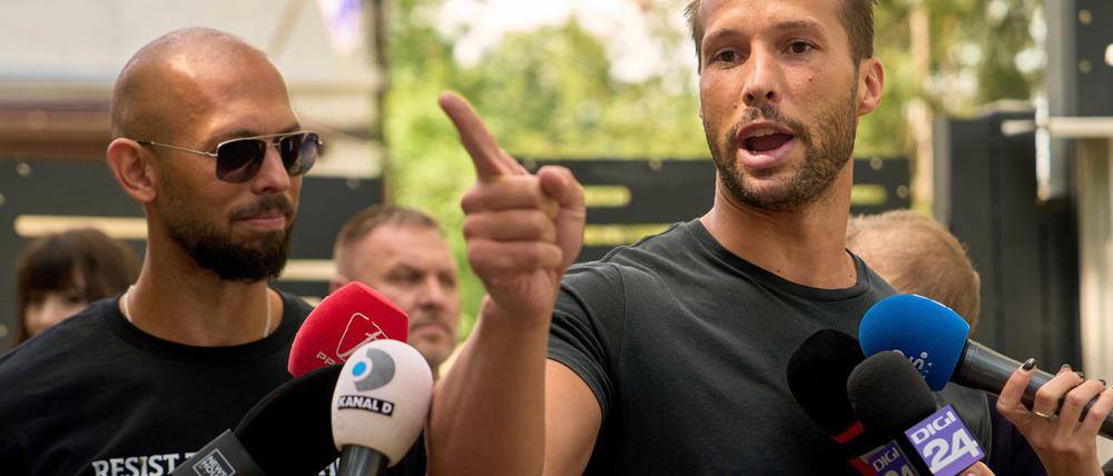 Andrew Tate (links) schaut zu seinem Bruder Tristan Tate, der am 21. Mai vor einer Polizeistation in Voluntari in Rumänien redete.
