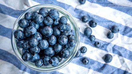 Beeren statt Chips oder Nüsschen: Heidelbeeren, auch Blaubeeren genannt, liegen auf einem Esstisch und werden gern gesnackt.