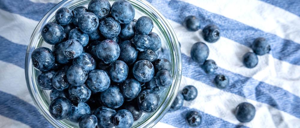 Beeren statt Chips oder Nüsschen: Heidelbeeren, auch Blaubeeren genannt, liegen auf einem Esstisch und werden gern gesnackt.