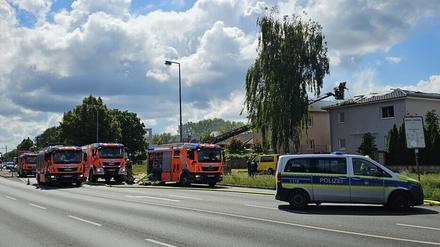 Drei Feuerwehrfahrzeuge und ein Polizeiwagen stehen in der Nähe des vom Brand betroffenen Hauses in Berlin-Staaken.