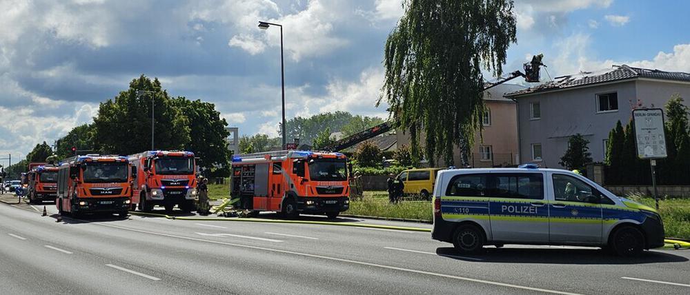 Drei Feuerwehrfahrzeuge und ein Polizeiwagen stehen in der Nähe des vom Brand betroffenen Hauses in Berlin-Staaken.