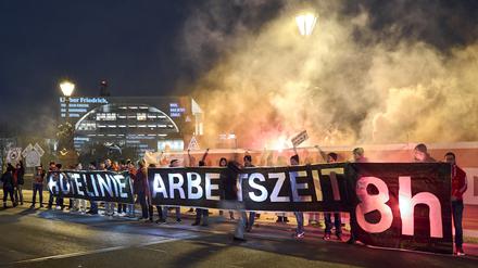 Mit einem Transparent mit der Aufschrift „Rote Linie Arbeitszeit 8h“ stehen Teilnehmer einer Protestaktion der IG Metall vor dem Bundeskanzleramt.