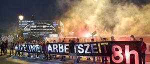 Mit einem Transparent mit der Aufschrift „Rote Linie Arbeitszeit 8h“ stehen Teilnehmer einer Protestaktion der IG Metall vor dem Bundeskanzleramt.