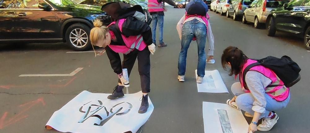 Aktivisten der Gruppe „Widerstands-Kollektiv“ sprühen Fahrrad-Piktogramme auf eine Straße.