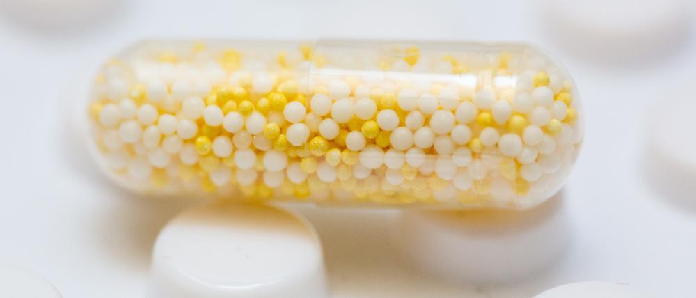 Eine Kapsel, die ein Nahrungsergänzungsmittel mit Kalium und Magnesium enthält, liegt auf einer Tablettenverpackung eines Arzneimittels.