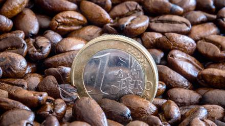 Eine Ein-Euro-Münze steht zwischen gerösteten Kaffeebohnen in einer Schale. Die Preise für Rohkaffee sind in den letzten Wochen stark gestiegen. 