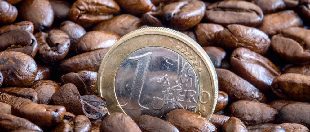 Eine Ein-Euro-Münze steht zwischen gerösteten Kaffeebohnen in einer Schale. Die Preise für Rohkaffee sind in den letzten Wochen stark gestiegen.