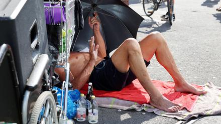 Ein Obdachloser schützt sich während des Hitzesommers 2022 in Berlin mit einem Schirm vor der Sonne. 