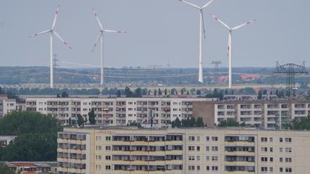 Vier Windkraftanlagen sind hinter den Hochhäusern von Marzahn zu sehen.