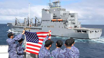 Die „Harvey Milk“ ist bei einem Manöver der US-Navy mit einem Schiff der japanischen Marine zu sehen, dessen Crew-Mitglieder die US-Flagge hochhalten.