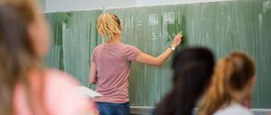 EineLehrerin schreibt im Mathematikunterricht Zahlen an eine Schultafel (Symbolbild).