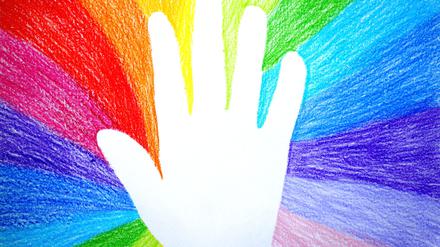 Abdruck einer Kinderhand in einer Regenbogenzeichnung.
