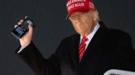 US Präsident Donald Trump steigt aus der Air Force One aus und präsentiert seinen Handybildschirmhintergrund. (Photo by SAUL LOEB / AFP)