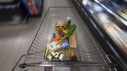 Ein Einkaufswagen mit Lebensmitteln steht in einem Supermarkt.