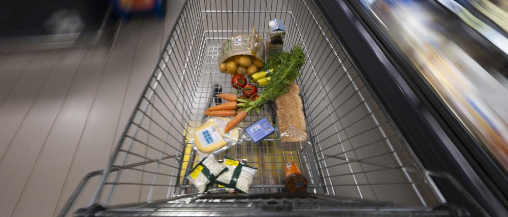 Ein Einkaufswagen mit Lebensmitteln steht in einem Supermarkt.