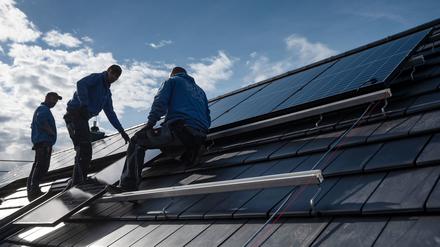 Mitarbeiter einer Firma montieren Photovoltaikmodule auf dem Dach eines Wohnhauses.