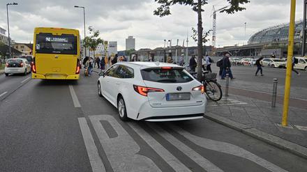Fahrgäste müssen auf der Fahrbahn aussteigen, weil ein Mietwagen die Haltestelle blockiert. 