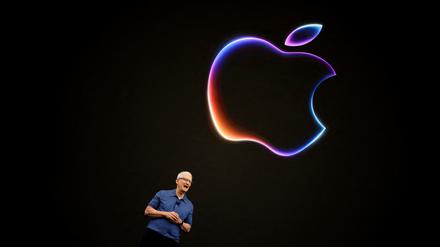 Der CEO von Apple Tim Cook steht vor einer schwarzen Wand mit einem Apple Symbol. 