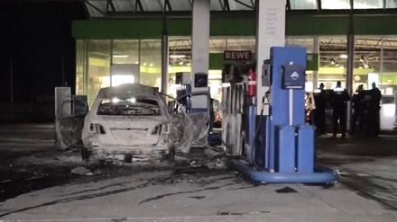 Ein ausgebranntes Fahrzeug steht an einer Zapfsäule auf einer Tankstelle in Hannover. 
