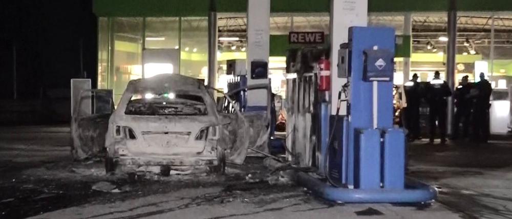 Ein ausgebranntes Fahrzeug steht an einer Zapfsäule auf einer Tankstelle in Hannover.