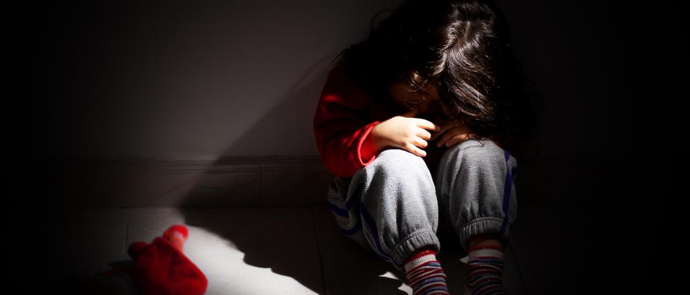 young girl sitting down alone in the dark.