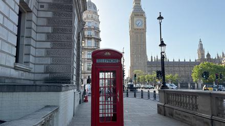 ARCHIV - 22.05.2025, Großbritannien, London: Eine rote Telefonzelle steht vor dem Glockenturm mit dem Big Ben. 