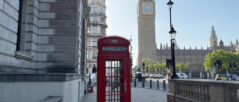 ARCHIV - 22.05.2025, Großbritannien, London: Eine rote Telefonzelle steht vor dem Glockenturm mit dem Big Ben. 