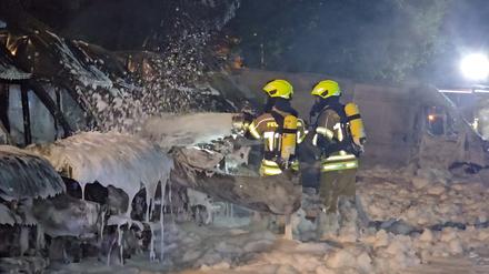 Einsatzkräfte der Feuerwehr löschen Brände an Transportern. 
