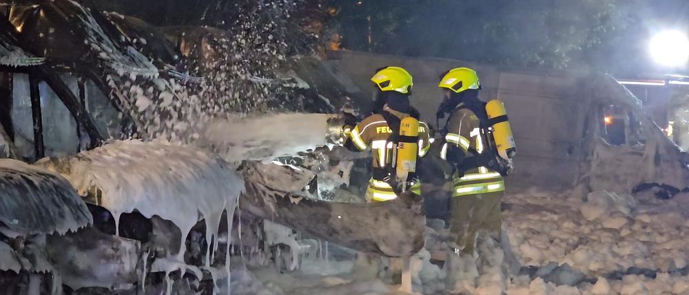 Einsatzkräfte der Feuerwehr löschen Brände an Transportern. 