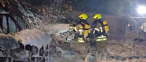 Einsatzkräfte der Feuerwehr löschen Brände an Transportern. 