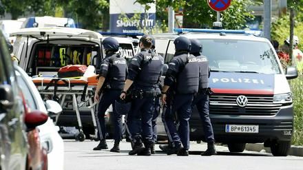 Einsatzkräfte der Polizei stehen in der Nähe des Tatorts an einer Grazer Schule.