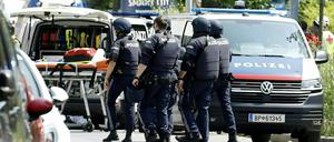 Einsatzkräfte der Polizei stehen in der Nähe des Tatorts an einer Grazer Schule.