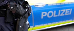 Ein Polizist steht vor einem Einsatzfahrzeug der Polizei. (Symbolbild)