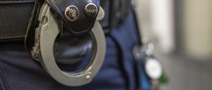 Eine Handschelle hängt am Gürtel eines Polizisten.