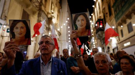 People hold up photos of late anti-corruption journalist Daphne Caruana Galizia during a protest march on the sixth anniversary of her assassination.