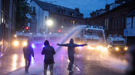 Randalierer vor einer Reihe von Einsatzfahrzeugen der Polizei im nordirischen Ballymena. 
