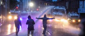 Randalierer vor einer Reihe von Einsatzfahrzeugen der Polizei im nordirischen Ballymena. 