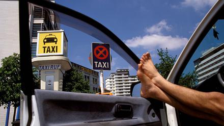 Konkurrenzlos glücklich: Ein Berliner Taxifahrer streckt am Anhalter Bahnhof die nackten Beine vom Fahrersitz an die geöffneten Autotür.