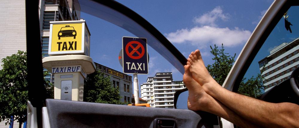 Konkurrenzlos glücklich: Ein Berliner Taxifahrer streckt am Anhalter Bahnhof die nackten Beine vom Fahrersitz an die geöffneten Autotür.