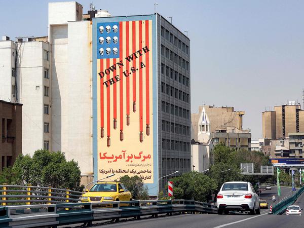 TOPSHOT - Vehicles move along the Karim Khan Zand Bridge past the "Down with the USA" mural painted on the side of the National Organisation of Educational Testing building in central Tehran on June 13, 2025. Israel unleashed a wave of strikes on Iran on June 13, hitting about 100 targets including nuclear facilities and military command centres, and killing senior figures, among them the armed forces chief and top nuclear scientists. (Photo by AFP)