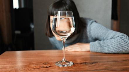 Eine Frau schaut durch ein Wasserglas.