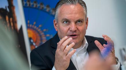 Münches neuer Wiesnchef Scharpf vor einem Foto des Riesenrades. 