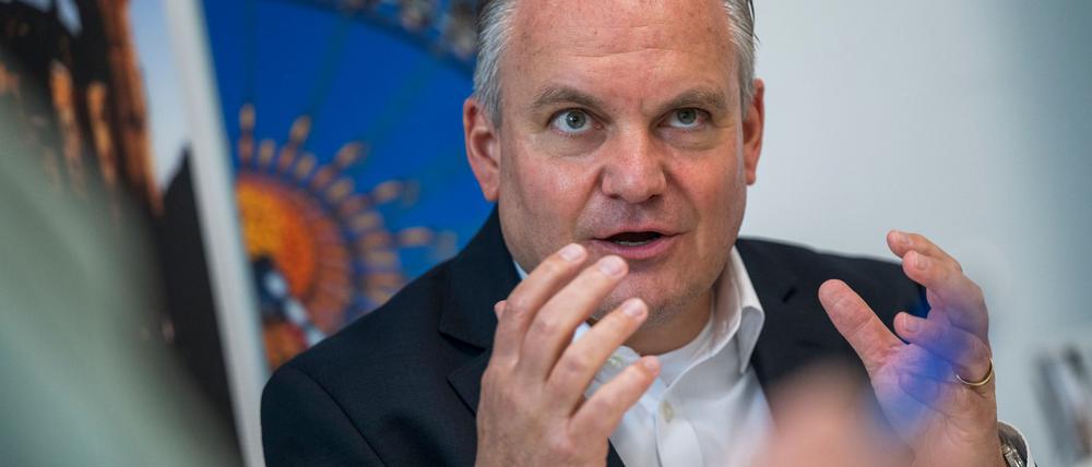 Münches neuer Wiesnchef Scharpf vor einem Foto des Riesenrades.