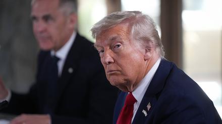 US-Präsident Donald Trump hört einer Frage eines Reporters zu, während er neben dem kanadischen Premierminister Mark Carney sitzt.